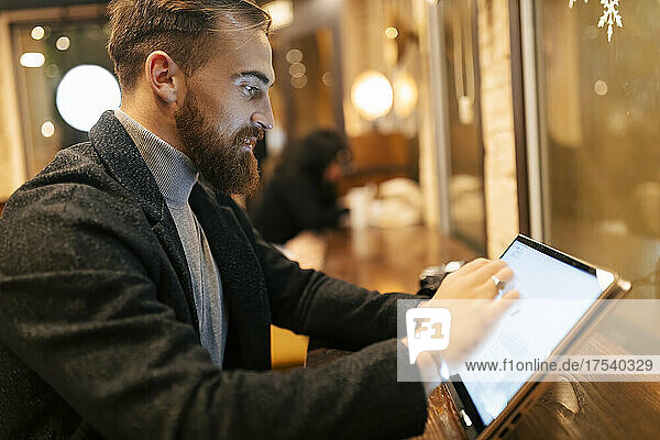 Freelancer using touch screen laptop at restaurant