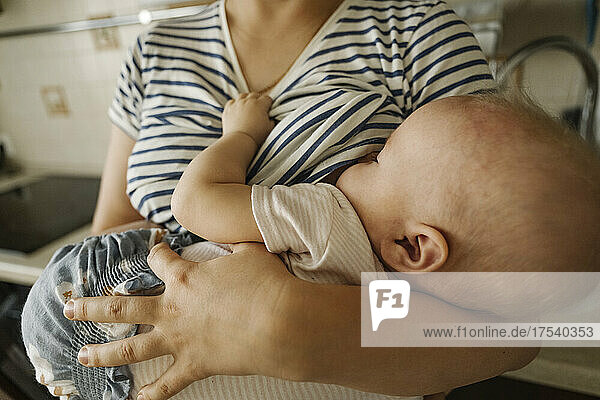 Mother's carrying toddler and breastfeeding at home