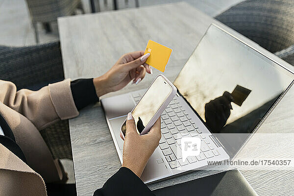 Geschäftsfrau mit Smartphone und Laptop  die per Kreditkarte bezahlt