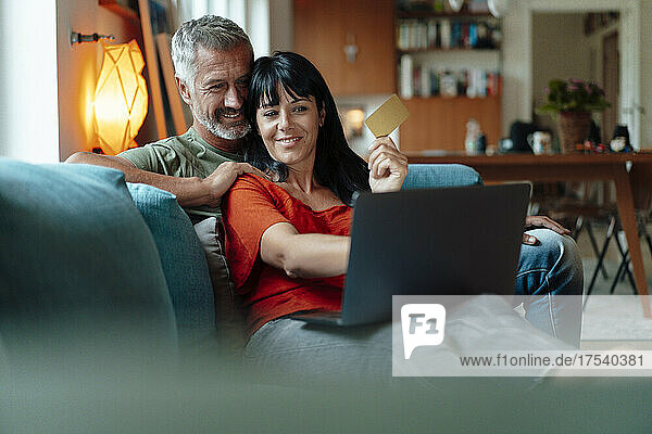 Lächelndes Paar beim Online-Shopping am Laptop zu Hause