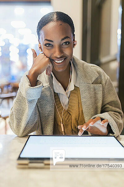 Smiling teenage girl using touch screen laptop at cafe