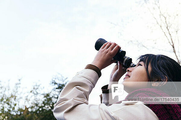 Young woman looking at sky through binoculars