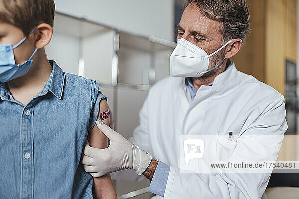 Doctor putting bandage on vaccinated boy at center