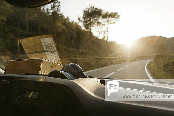 Package and cap on dashboard of van on sunny day