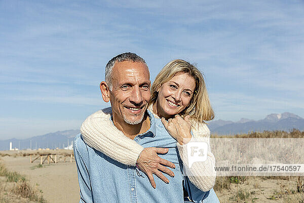 Woman embracing man on sunny day at sand dunes