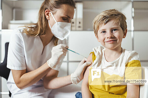 Smiling boy getting vaccinated by nurse at center