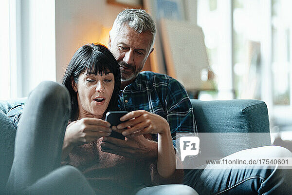 Man sharing smart phone with woman in living room