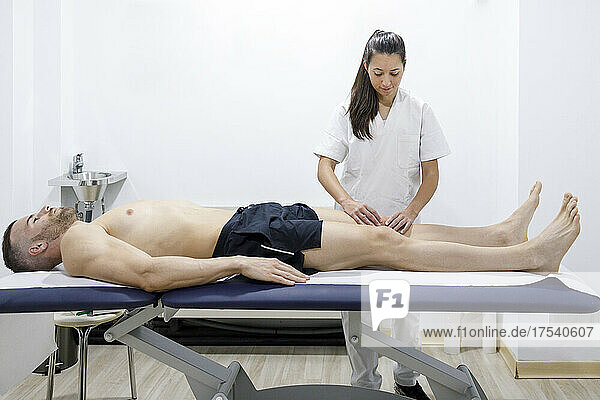 Physical therapist massaging athlete's leg at rehabilitation center