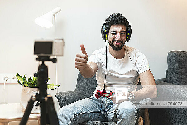 Gamer winking and showing thumbs up to camera at home