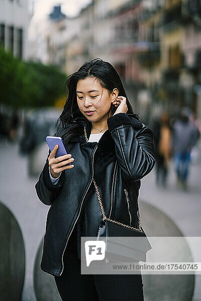 Junge Frau benutzt Mobiltelefon auf Fußweg