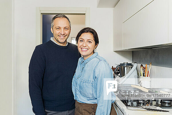 Smiling couple standing together by kitchen counter at home