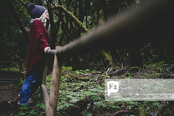 Woman leaning on railing in forest