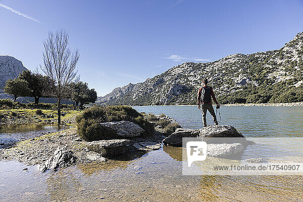 Hiker standing on rock and admiring mountains  Cuber Dam  Mallorca  Balearic Islands  Spain