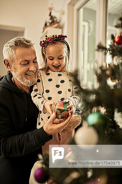 Grandfather giving gift to granddaughter on christmas at home