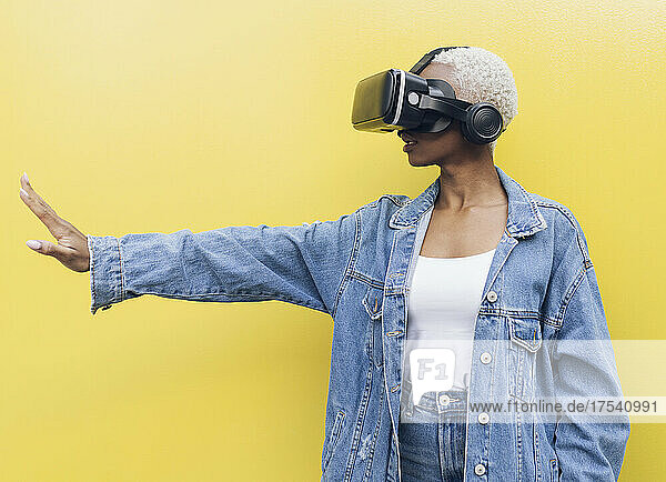 Young woman with virtual reality headset against yellow background