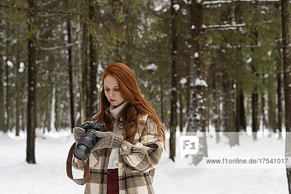Redhead woman looking at camera in winter forest