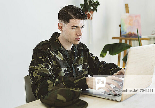 Young army man using laptop at home
