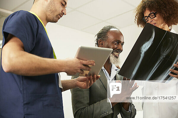 Smiling patient looking at X-ray with healthcare workers in medical room