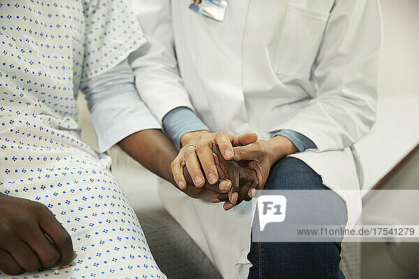 Doctor holding hands and consoling patient in medical room