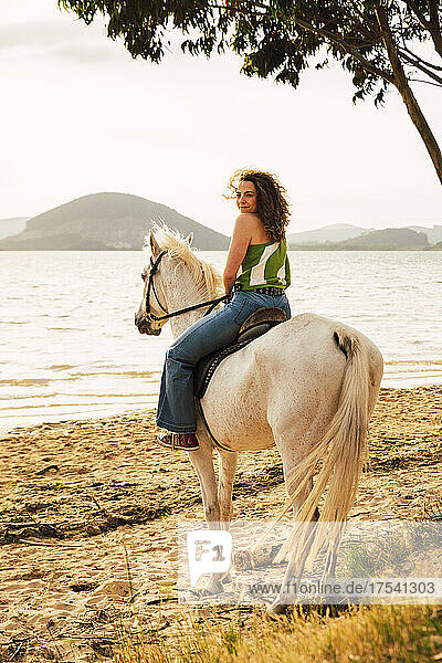 Young woman enjoying horse riding at waterfront