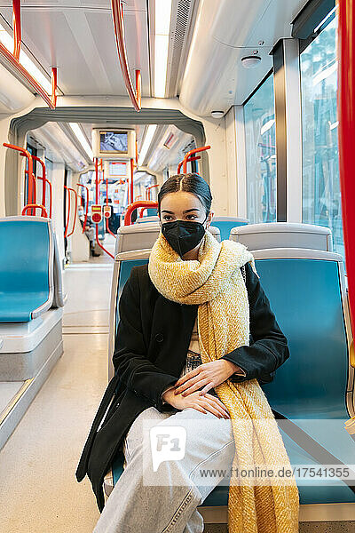 Teenage girl wearing protective face mask in bus