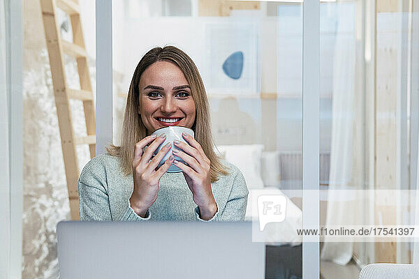 Smiling businesswoman holding coffee cup at studio