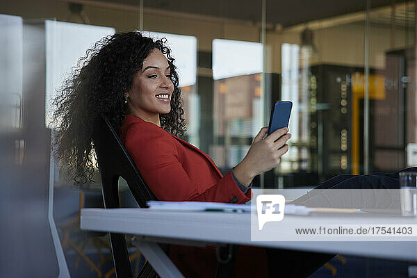 Smiling businesswoman using smart phone in office