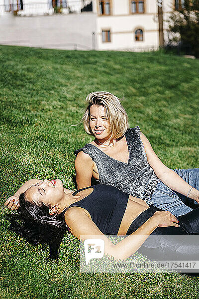 Happy blond woman looking at friends relaxing on lawn