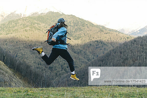 Backpacker jumping in mountain landscape