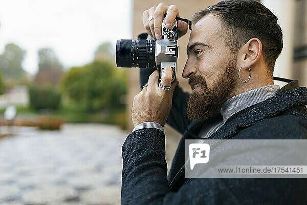 Young bearded man photographing through camera