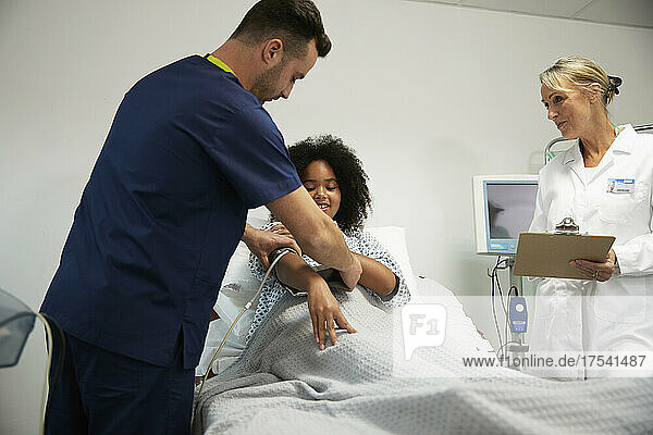 Nurse assisting patient to wear blood pressure gauge in hospital ward