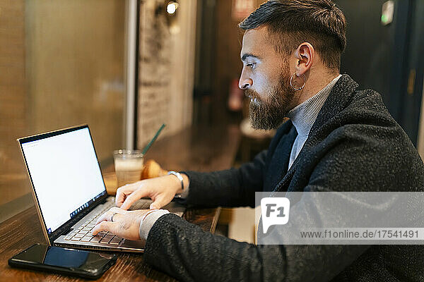Freelancer using laptop typing at restaurant