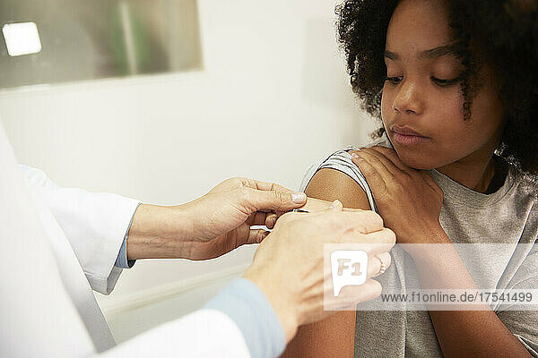 Doctor sticking adhesive bandage on patient arm