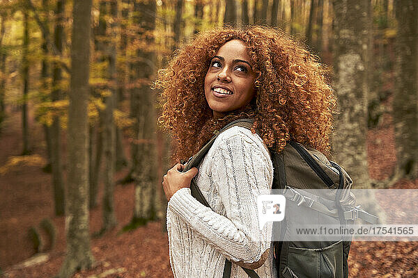 Contemplative woman with backpack in autumn forest
