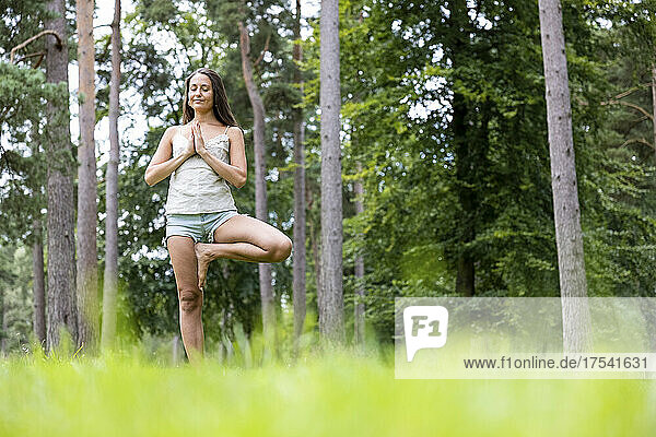 Woman standing on one leg practicing yoga in forest at Cannock Chase