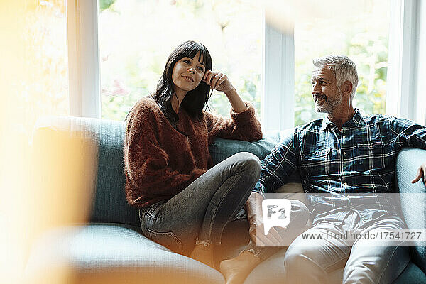Man talking with woman sitting on sofa at home
