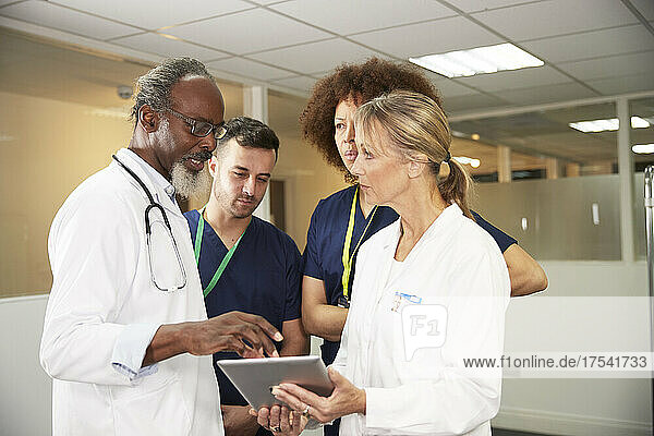 Male doctor explaining colleagues over tablet PC in medical room