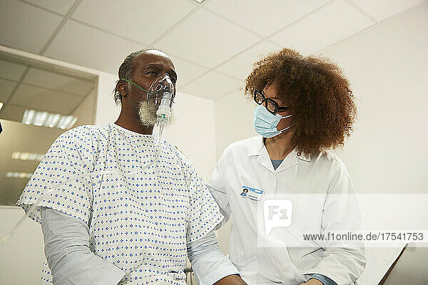 Doctor with protective face mask motivating patient in medical room