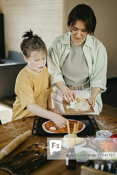 Boy preparing pizza with mother at home