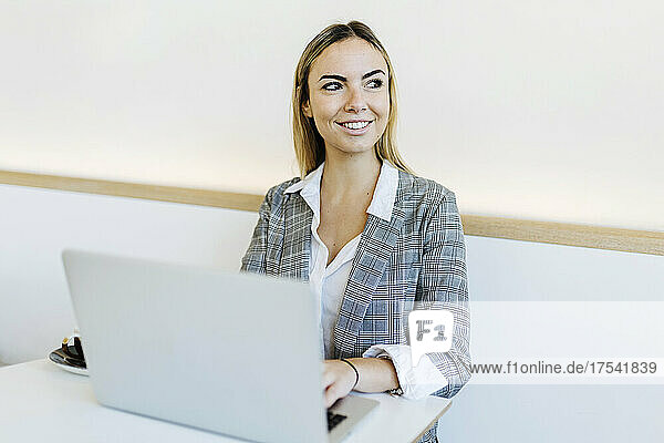 Smiling businesswoman with laptop on table in cafe