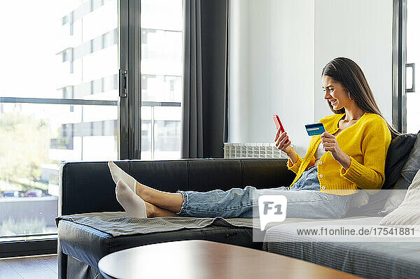 Smiling woman with credit card doing online shopping at home