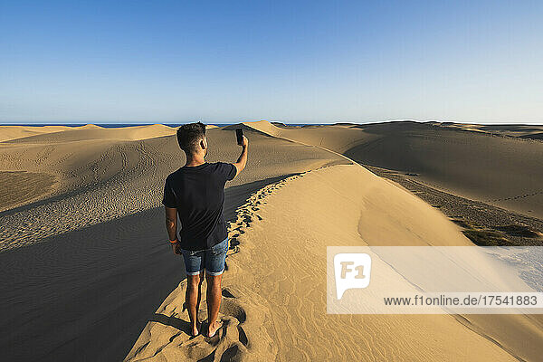 Man taking selfie through smart phone standing on sand dune  Grand Canary  Canary Islands  Spain