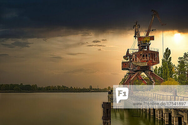 Ukraine  Kyiv Oblast  Pripyat  Abandoned crane on bank of Pripyat River at sunset