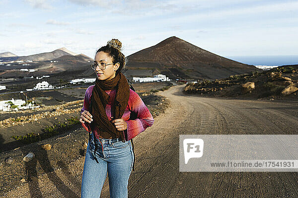 Young woman with backpack hiking on dirt road