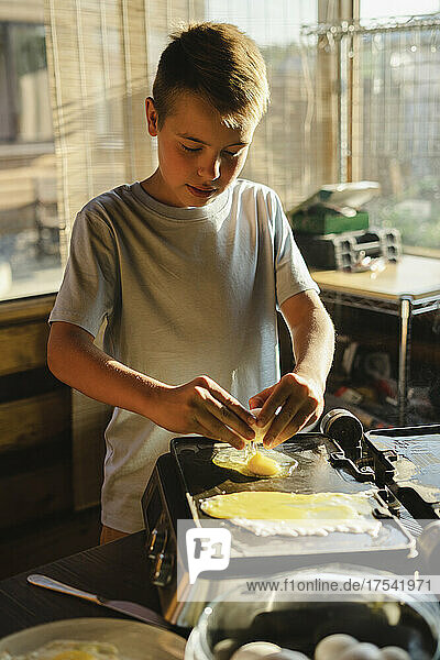 Boy preparing fried egg in kitchen at home