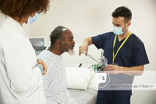 Nurse helping patient with oxygen mask at hospital