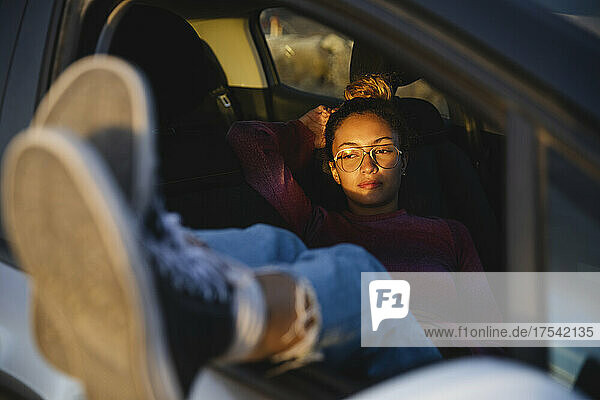 Young woman resting in car at sunset