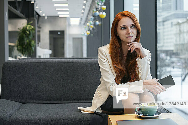 Thoughtful working woman sitting on sofa in office cafeteria