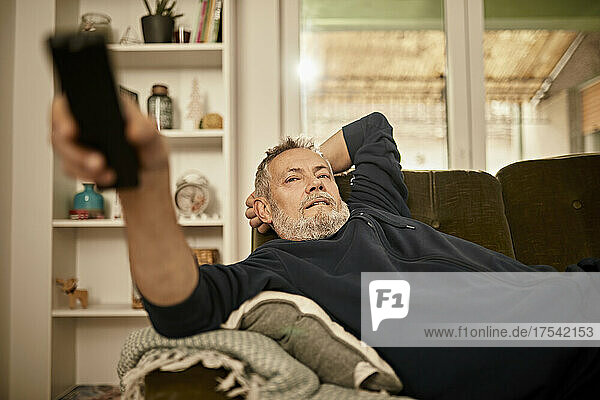 Relaxed man watching TV at home