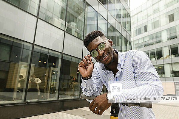 Smiling man wearing eyeglasses in front of building